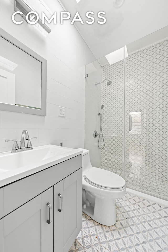 full bath with vanity, a shower stall, toilet, and tile walls