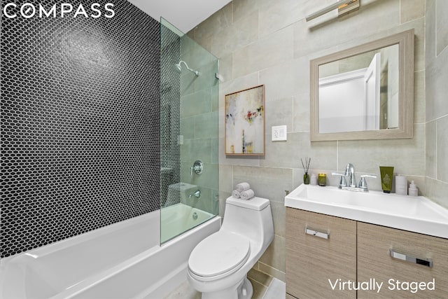 full bathroom with bath / shower combo with glass door, vanity, toilet, and tile walls