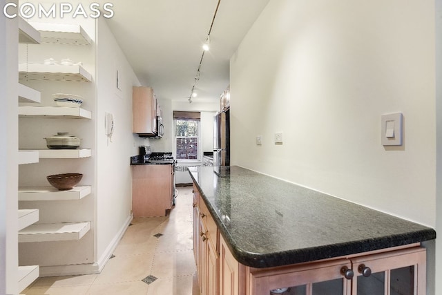 kitchen featuring gas range oven, rail lighting, stainless steel refrigerator, and light tile patterned flooring