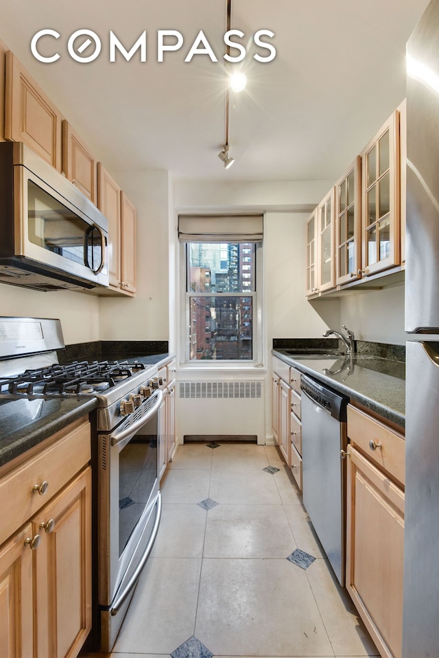150 E 61st St Unit 5C, New York City, NY 10065 - kitchen featuring appliances with stainless steel finishes, radiator, dark countertops, glass insert cabinets, and light brown cabinets