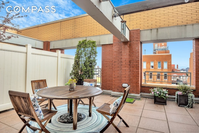 view of patio featuring outdoor dining area, fence, and a balcony