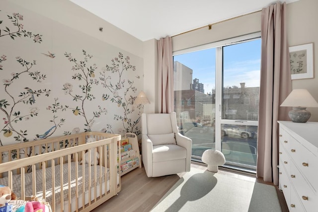 bedroom with light hardwood / wood-style flooring and a crib