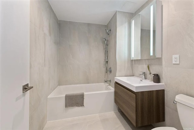 full bathroom with tile walls, vanity, tiled shower / bath combo, and toilet