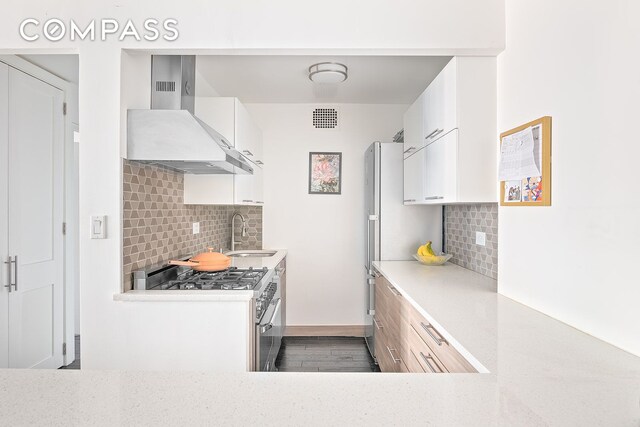 kitchen featuring white cabinetry, wall chimney exhaust hood, sink, and decorative backsplash