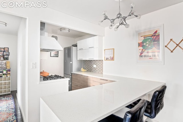 kitchen featuring white cabinetry, backsplash, stainless steel fridge, and kitchen peninsula