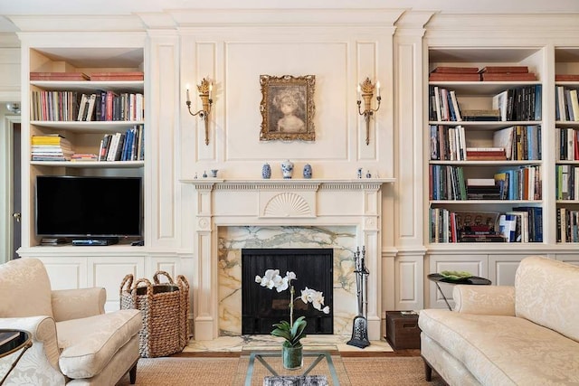 sitting room with built in shelves and a high end fireplace