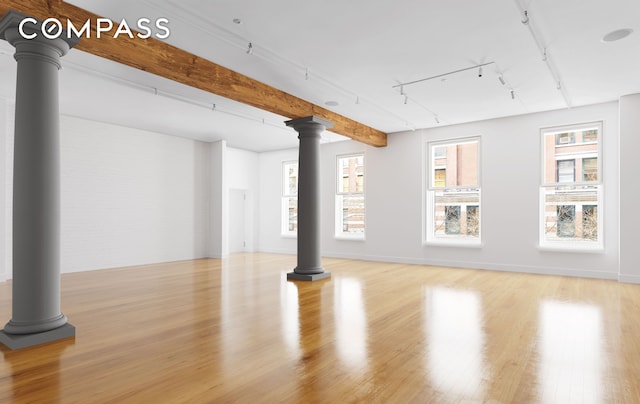 below grade area featuring rail lighting, baseboards, and wood finished floors