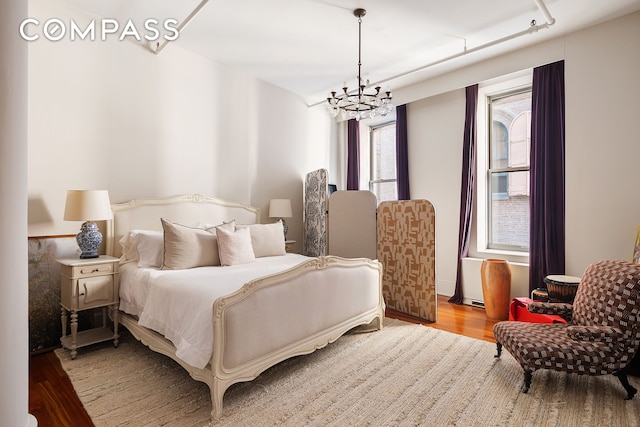 bedroom with wood finished floors and a notable chandelier