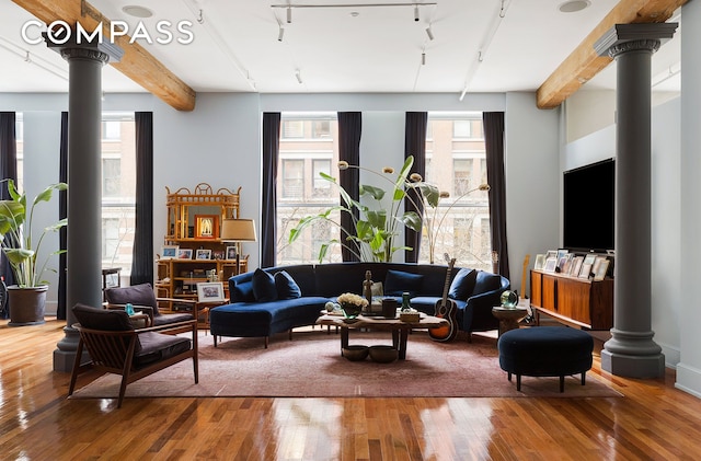 living room with wood-type flooring, decorative columns, track lighting, and beamed ceiling