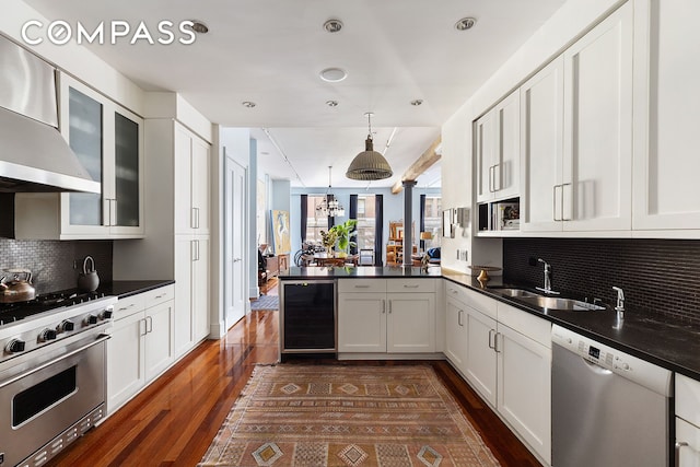 kitchen featuring beverage cooler, a peninsula, dark countertops, and stainless steel appliances