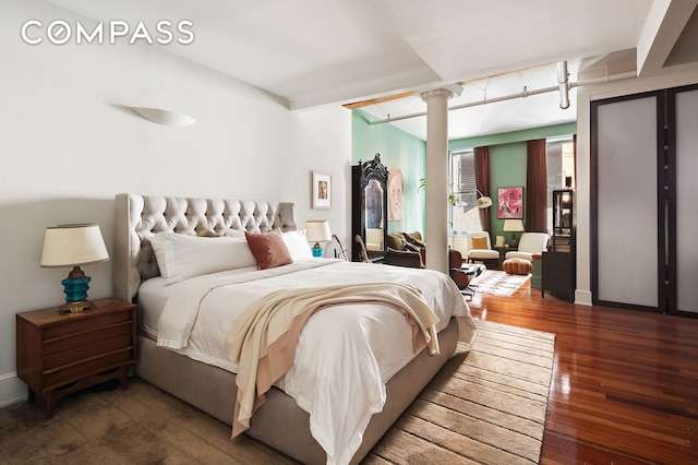 bedroom featuring decorative columns and wood finished floors