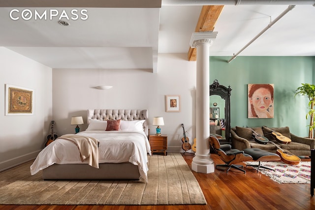 bedroom with baseboards, decorative columns, and wood finished floors