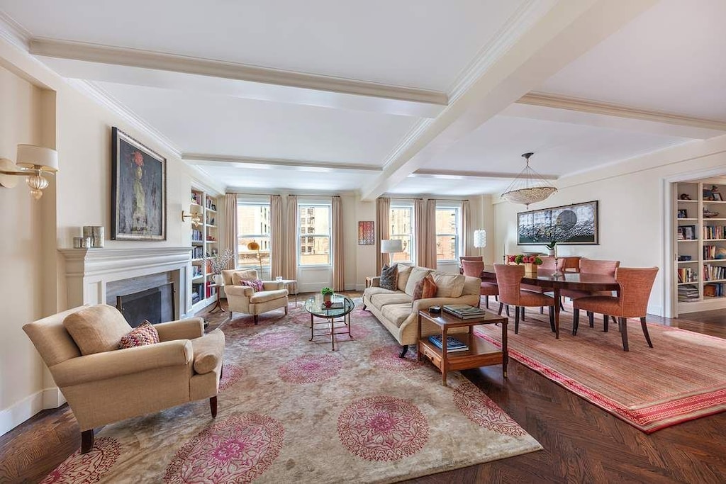 living room with built in features, baseboards, ornamental molding, a fireplace, and beam ceiling