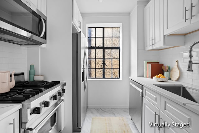 kitchen with tasteful backsplash, sink, white cabinets, and appliances with stainless steel finishes