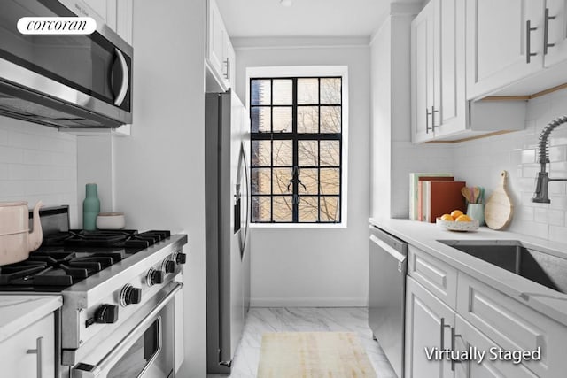 kitchen featuring appliances with stainless steel finishes, sink, white cabinets, decorative backsplash, and light stone countertops