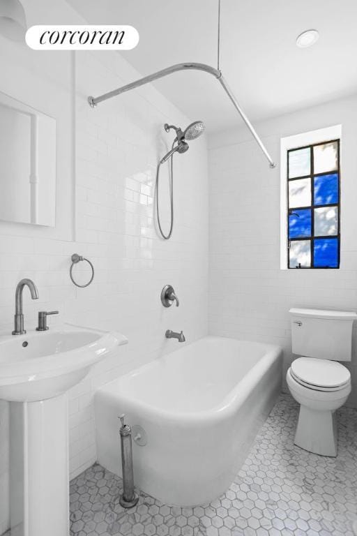 full bathroom with tile patterned floors, toilet, sink, tiled shower / bath, and tile walls