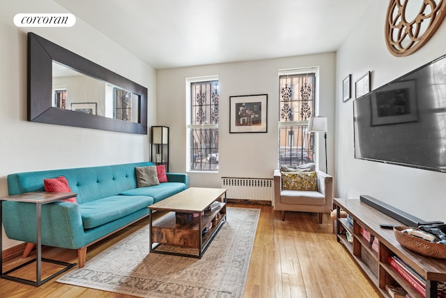 living area with visible vents, hardwood / wood-style floors, and radiator heating unit