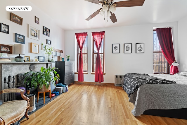 bedroom featuring baseboards, ceiling fan, wood finished floors, and radiator