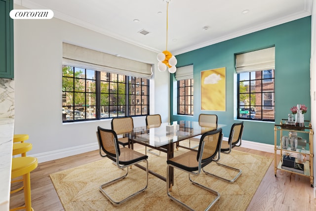 dining space featuring light hardwood / wood-style flooring and ornamental molding