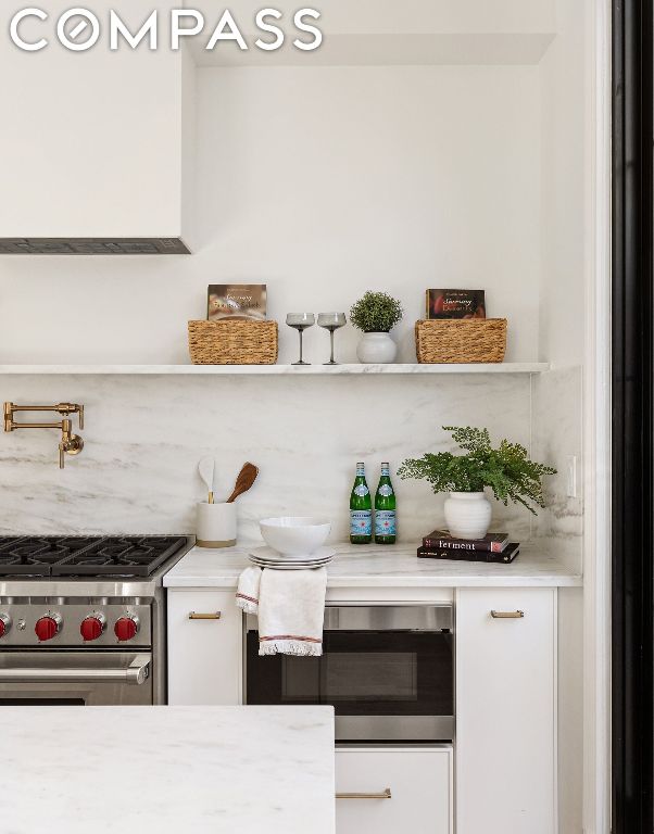 bar with tasteful backsplash, white cabinetry, and high end stainless steel range