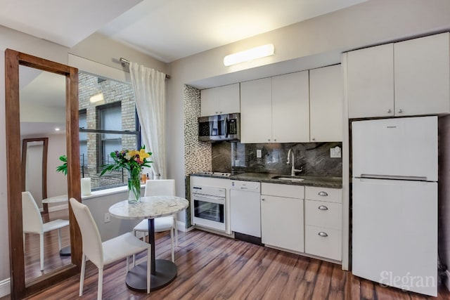 kitchen featuring white appliances, dark wood-style flooring, a sink, white cabinetry, and backsplash