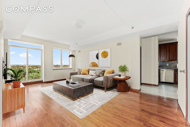 living room featuring light wood-style flooring, visible vents, and baseboards