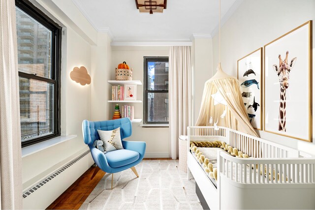 bedroom with a crib, ornamental molding, a baseboard heating unit, and light hardwood / wood-style floors