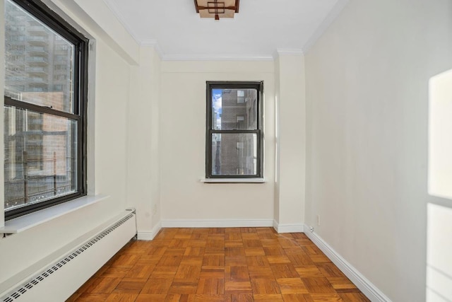 empty room featuring light parquet floors, ornamental molding, and baseboard heating