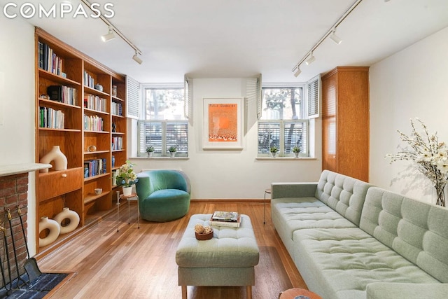 sitting room featuring a fireplace, a wealth of natural light, rail lighting, and wood-type flooring