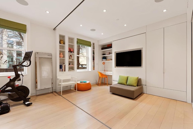 exercise area with light hardwood / wood-style flooring and built in features