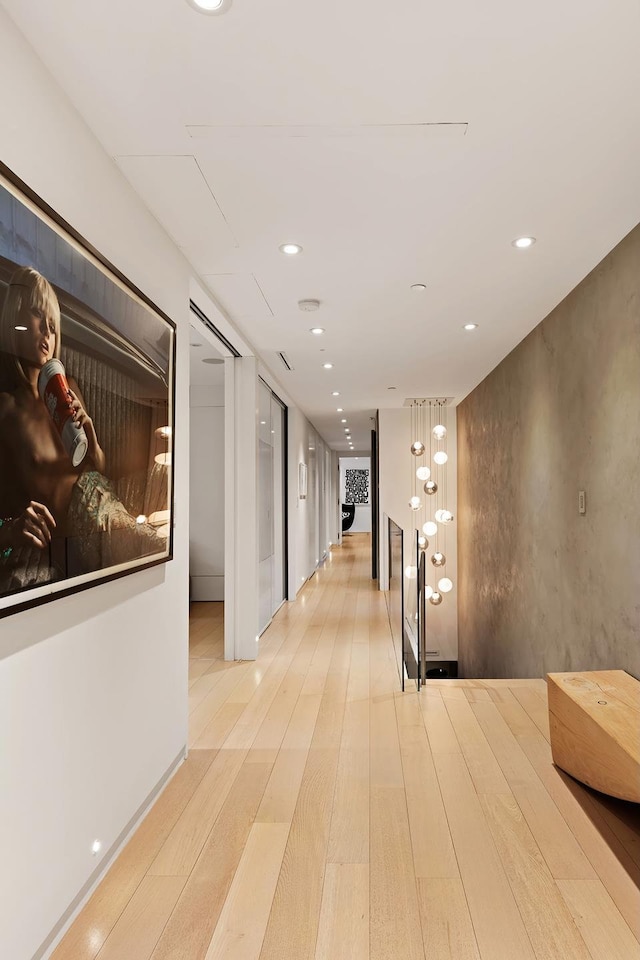 hallway with recessed lighting, light wood-style flooring, and an upstairs landing