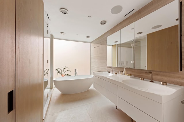 bathroom with a freestanding bath, tile patterned flooring, double vanity, and a sink
