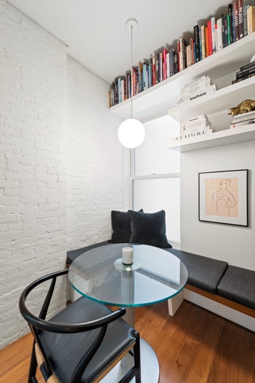 dining room with hardwood / wood-style flooring and brick wall