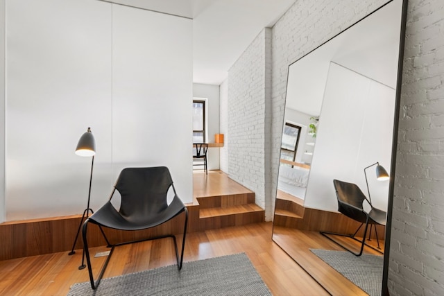 living area featuring brick wall, hardwood / wood-style floors, and wooden walls