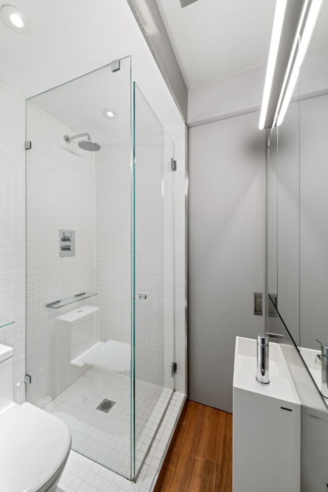 bathroom with a stall shower, vanity, toilet, and wood finished floors