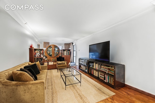 living area with ornamental molding, wood finished floors, and baseboards