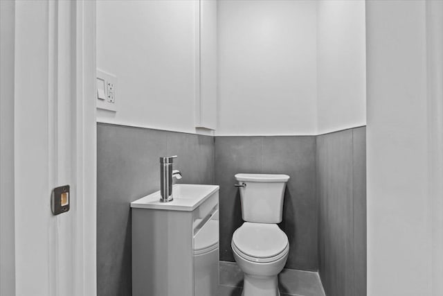 bathroom with a wainscoted wall, a sink, and toilet