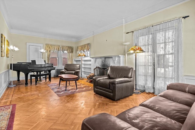 living room featuring radiator, a fireplace, crown molding, and wainscoting