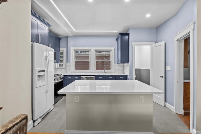 kitchen with a sink, blue cabinets, stainless steel appliances, and tasteful backsplash