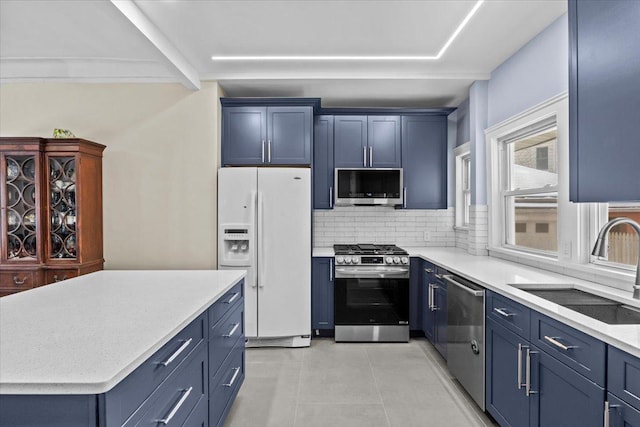 kitchen with blue cabinets, stainless steel appliances, and a sink