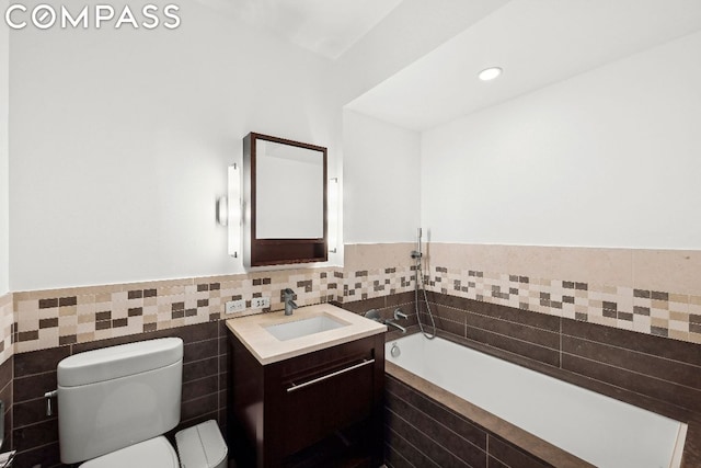 bathroom featuring a bathing tub, tile walls, vanity, and toilet