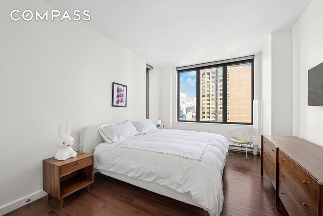 bedroom with a baseboard heating unit, baseboards, and dark wood-type flooring