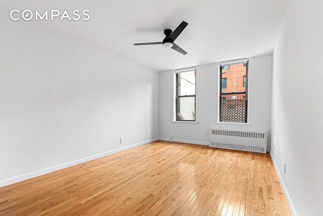 unfurnished room featuring radiator, ceiling fan, and light wood-type flooring