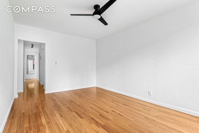 spare room with light wood finished floors, baseboards, and a ceiling fan