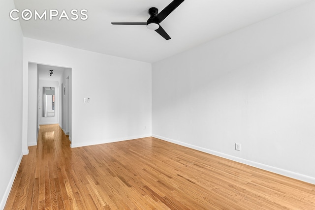 unfurnished room featuring ceiling fan, light wood-style flooring, and baseboards