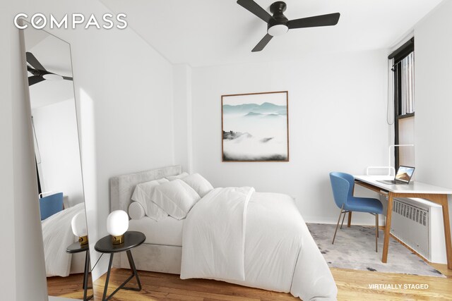 bedroom with radiator, hardwood / wood-style floors, and ceiling fan