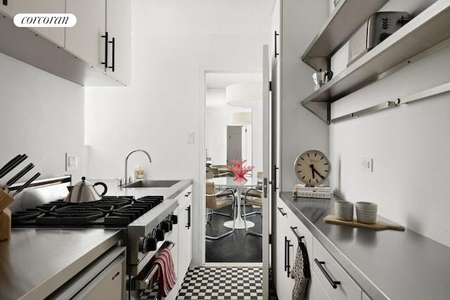 kitchen with high end stainless steel range oven, white cabinetry, and sink