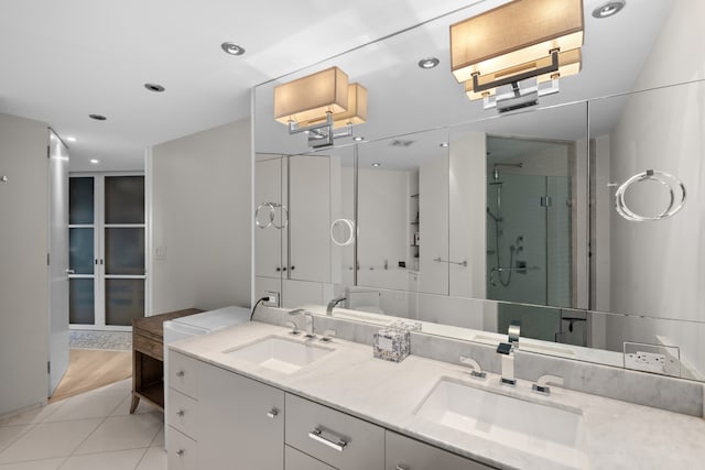 bathroom with tile patterned flooring, a sink, a shower stall, and double vanity