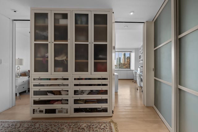 walk in closet with light wood-style floors