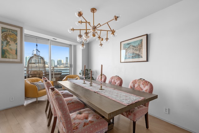 dining area featuring a chandelier, light wood finished floors, and a view of city